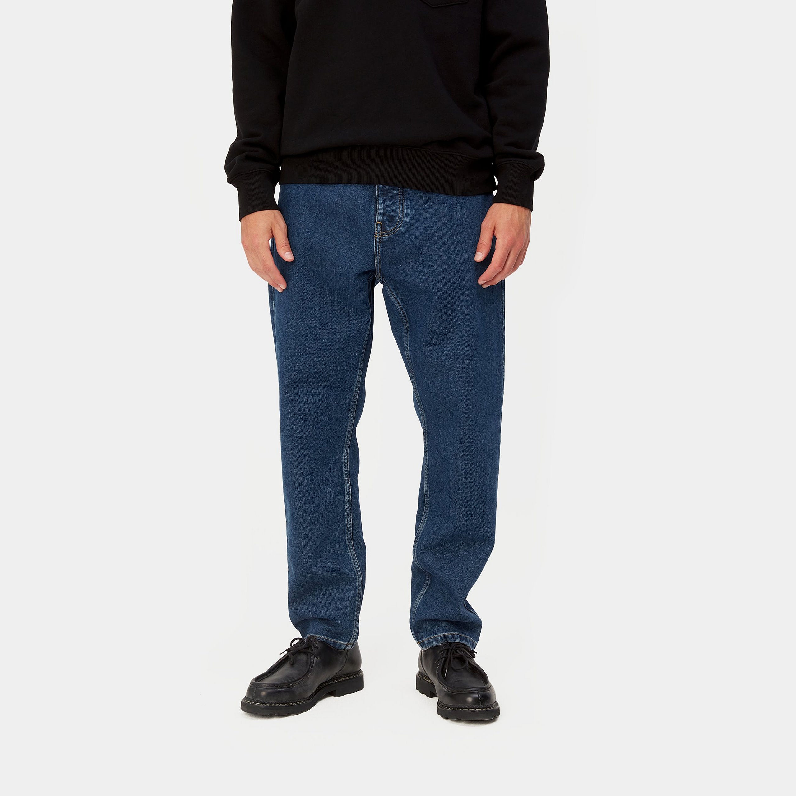 Dark blue denim Carhartt trousers with woven logo on back pocket. Free UK shipping on orders over £50.