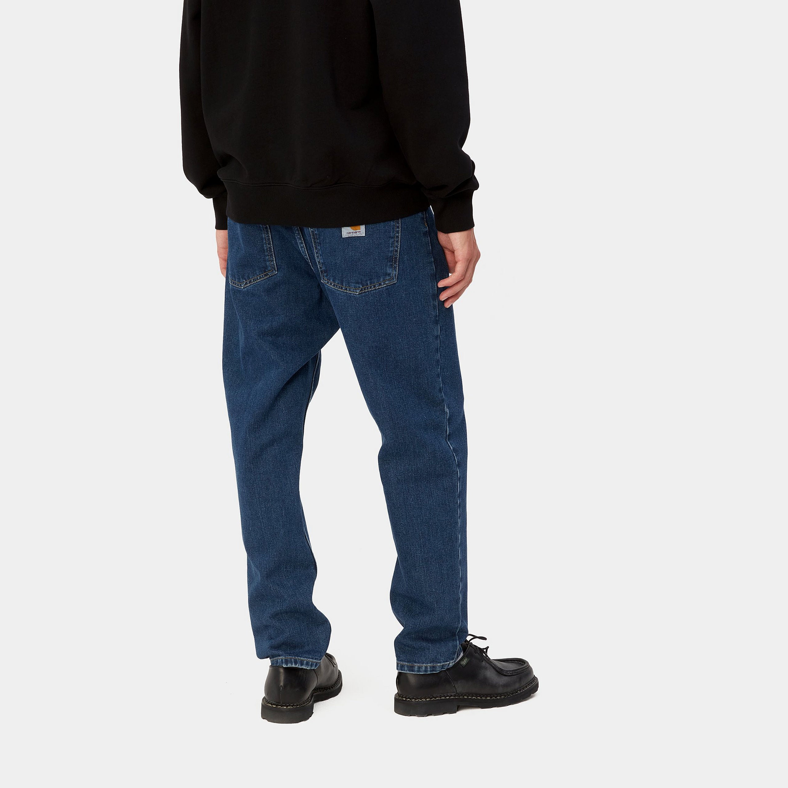 Dark blue denim Carhartt trousers with woven logo on back pocket. Free UK shipping on orders over £50.
