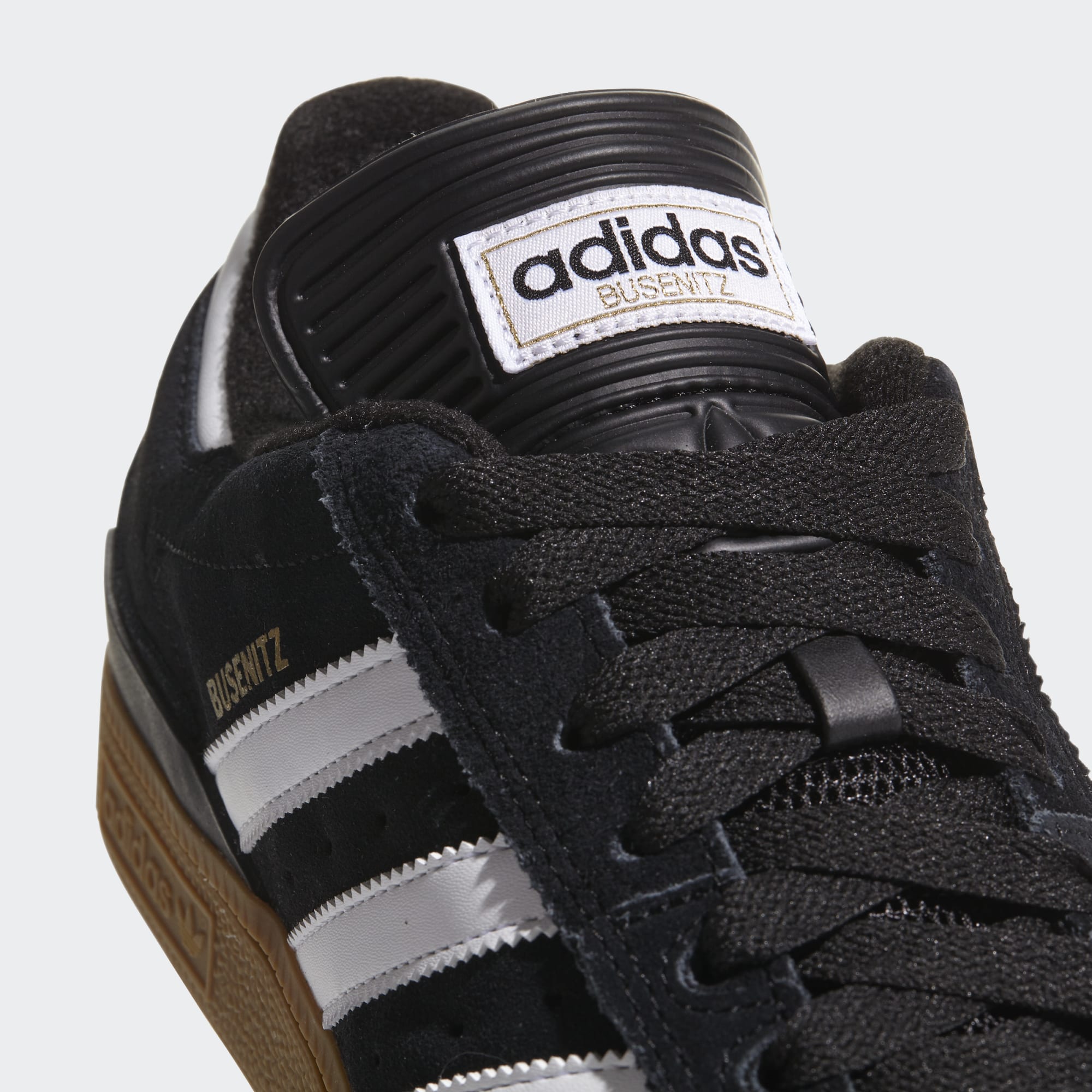 Black Adidas Busenitz sneaker with white stripes on a light gray background